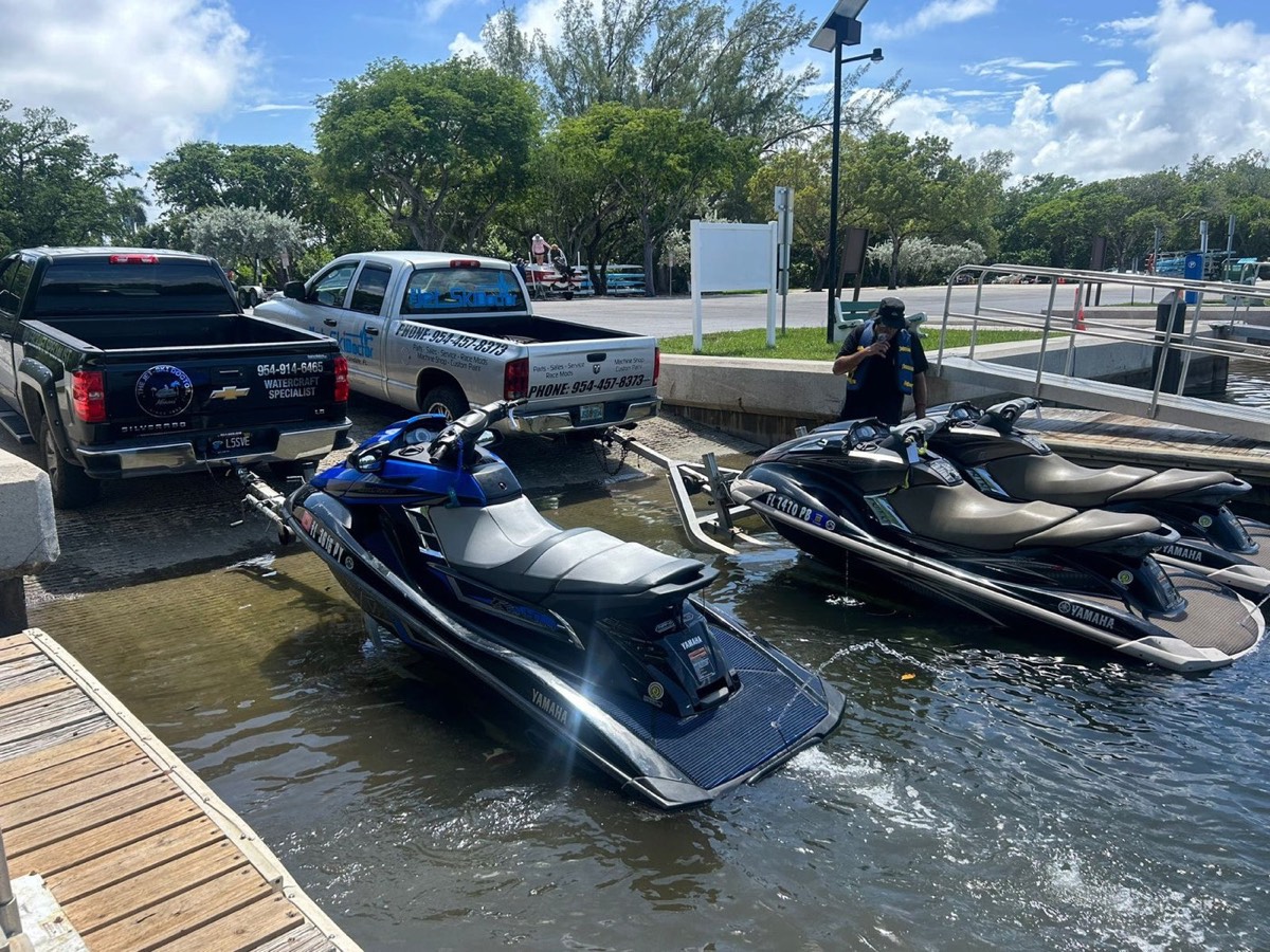 Jet Ski Doctor technicians and service trucks at a boat ramp